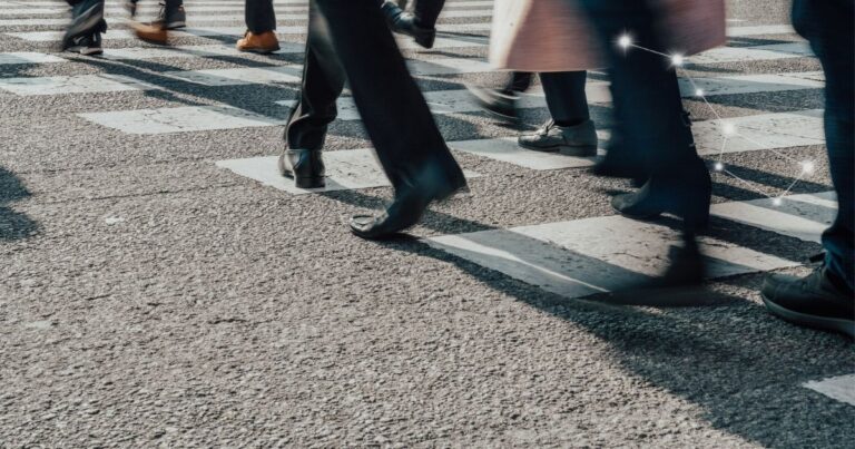 Pessoas caminhando em travessia urbana durante a rotina diária, representando conforto contínuo ao longo do dia